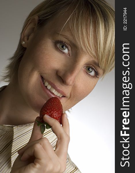 Young blond woman holding strawberry in her hand