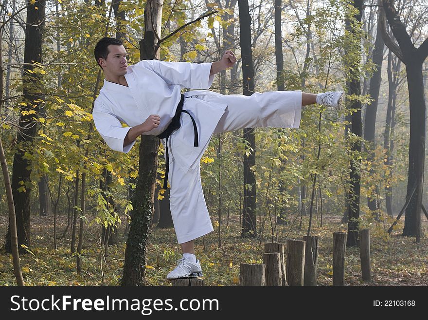 Man wearing Gi (Karate uniform) and black belt shown in a kick. Man wearing Gi (Karate uniform) and black belt shown in a kick