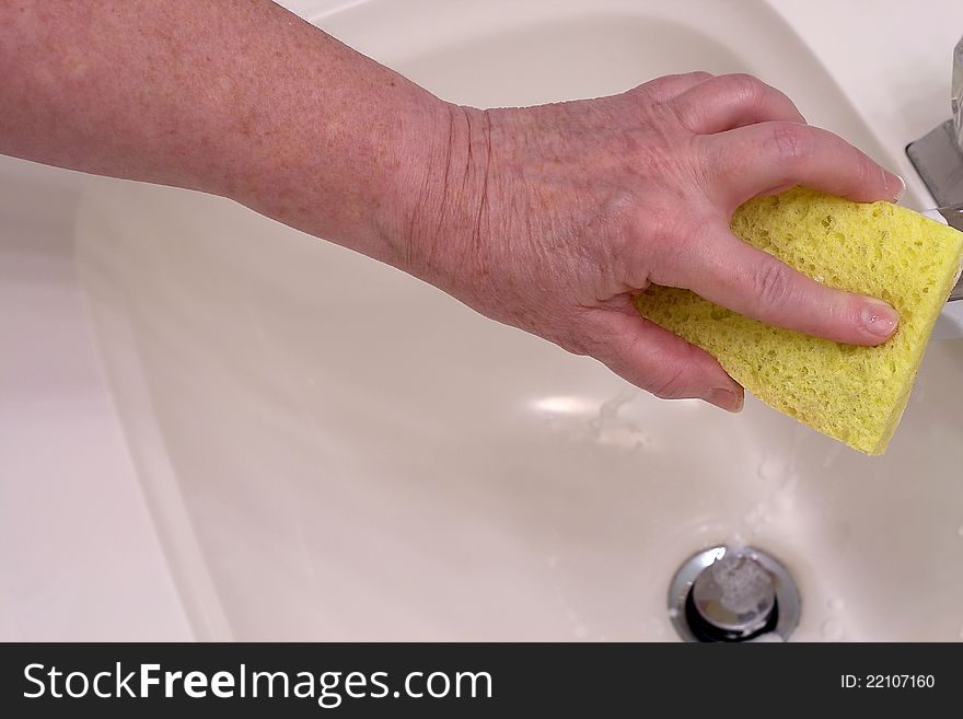A hand holding a sponge doing a daily housekeeping chore. A hand holding a sponge doing a daily housekeeping chore.
