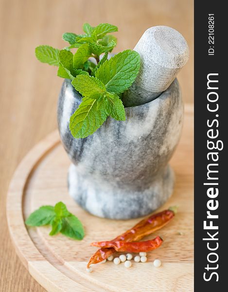 Fragrant mint in a ceramic mortar and spices on wooden background