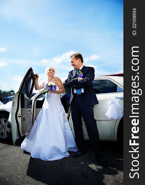 Happy bride and groom about wedding limousine