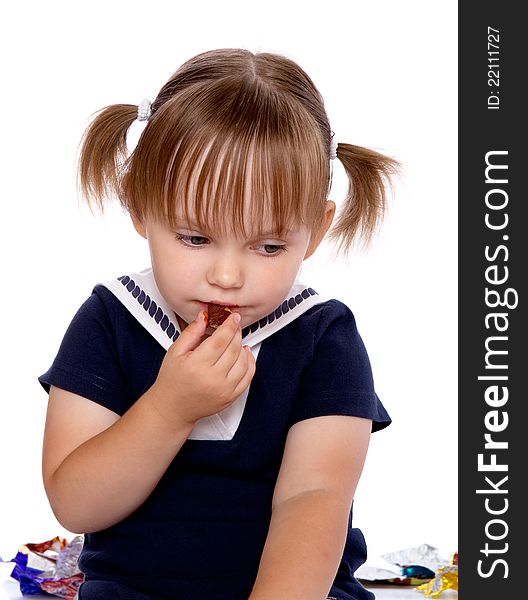 The little girl eats a chocolate. Isolated on a white background