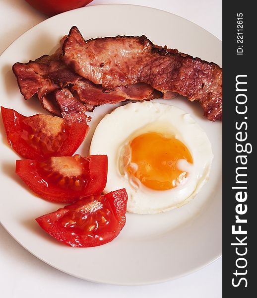 Fried egg with bacon and tomato close up