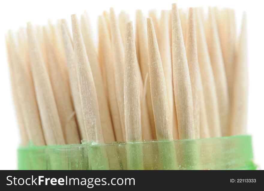 A close-up shot of wooden toothpicks in a plastic case against a white background. A close-up shot of wooden toothpicks in a plastic case against a white background