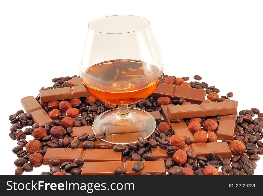 Glass with cognac with chocolate, coffee and nuts on a white background