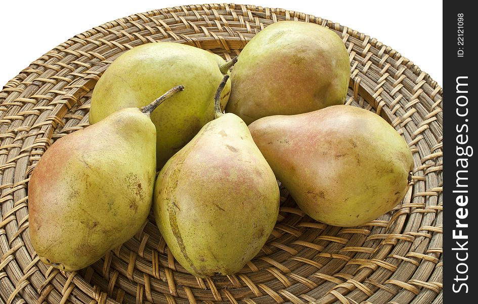 Fresh pears on wicker plate on white