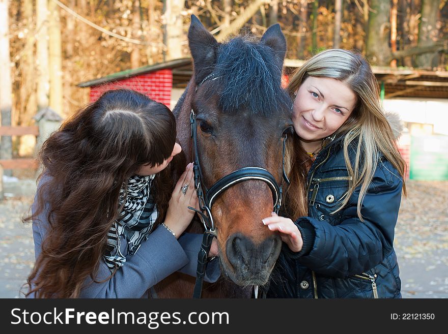 Two happy girls playing with a horse and smiling. Two happy girls playing with a horse and smiling