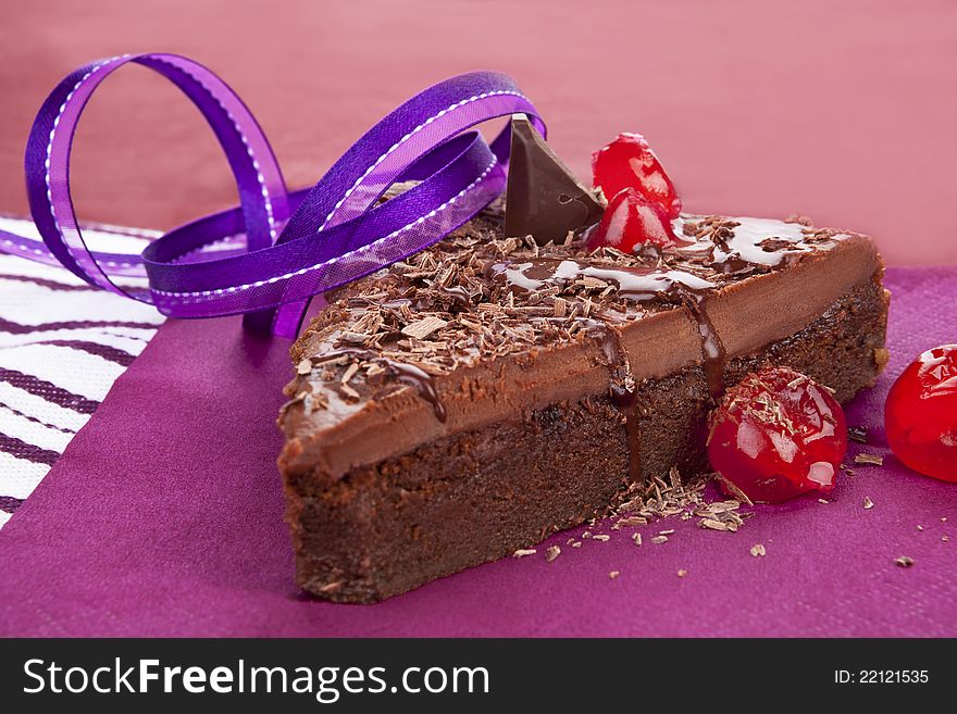 Delicious chocolate cake on purple background. Culinary sweet desert still life. Delicious chocolate cake on purple background. Culinary sweet desert still life.