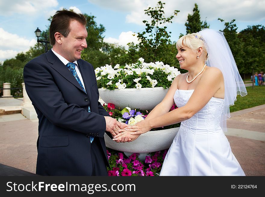 Happy groom and happy bride near flowers bed in wedding walk