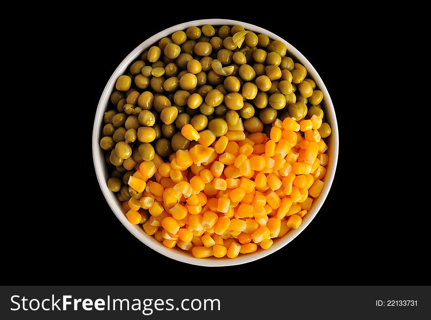 A plate with corn and peas, isolated, on a black background. A plate with corn and peas, isolated, on a black background