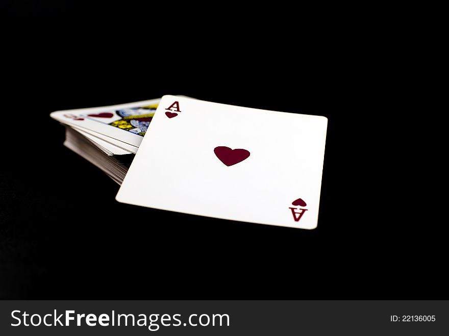 A pack of playing cards with the ace of hearts to top;black background. A pack of playing cards with the ace of hearts to top;black background
