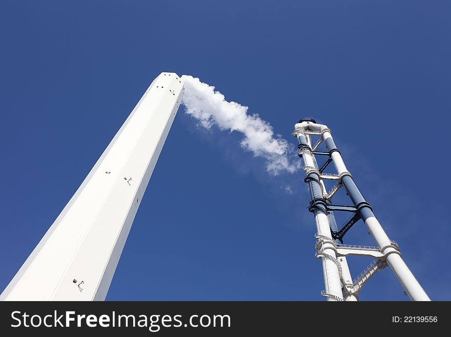 Smokestack with white smoke over blue sky. Smokestack with white smoke over blue sky