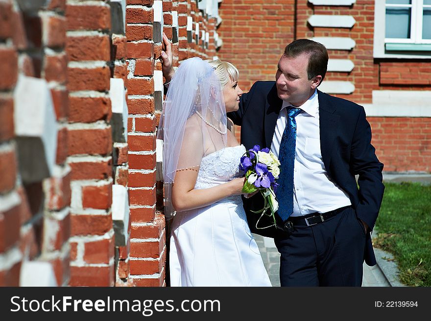 Happy Bride And Groom Near Red Brick Wall