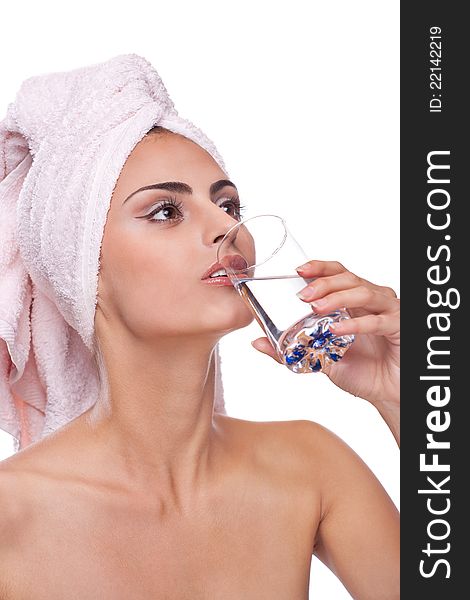 Beautiful brunette spa woman drinking water in towel on head
