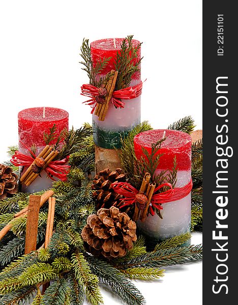 Trio of red, white and green festive candles with green cedar leaves & cinnamon tied on with twine among fresh green pine branches. Trio of red, white and green festive candles with green cedar leaves & cinnamon tied on with twine among fresh green pine branches.