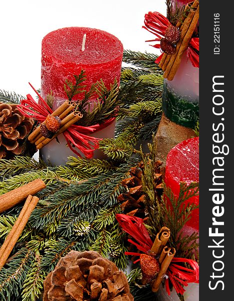 Red festive candles with green cedar leaves & cinnamon tied on with twine among fresh green pine branches. Red festive candles with green cedar leaves & cinnamon tied on with twine among fresh green pine branches.