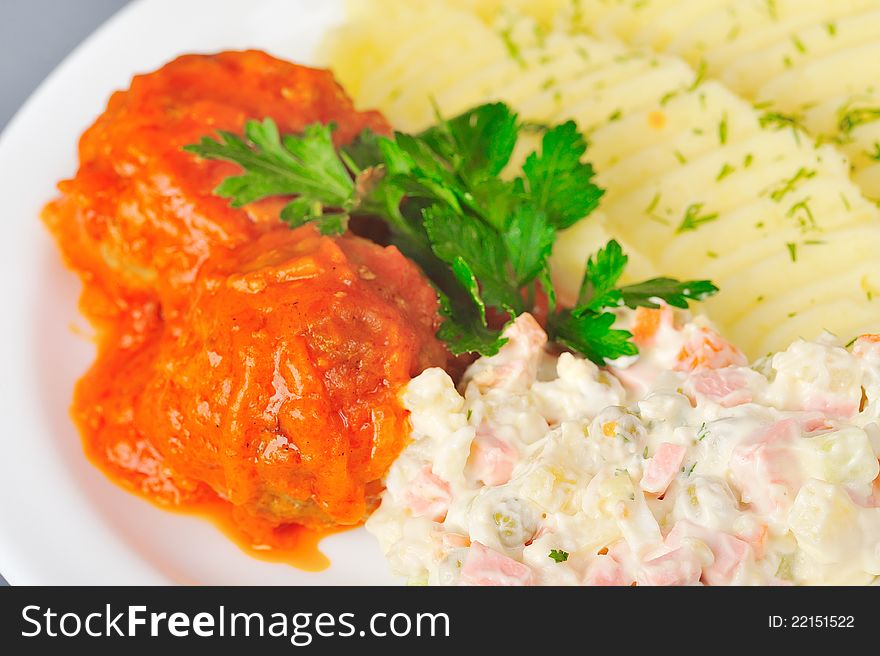 Meatball in tomato sauce with mashed potato and olivie salad. Meatball in tomato sauce with mashed potato and olivie salad