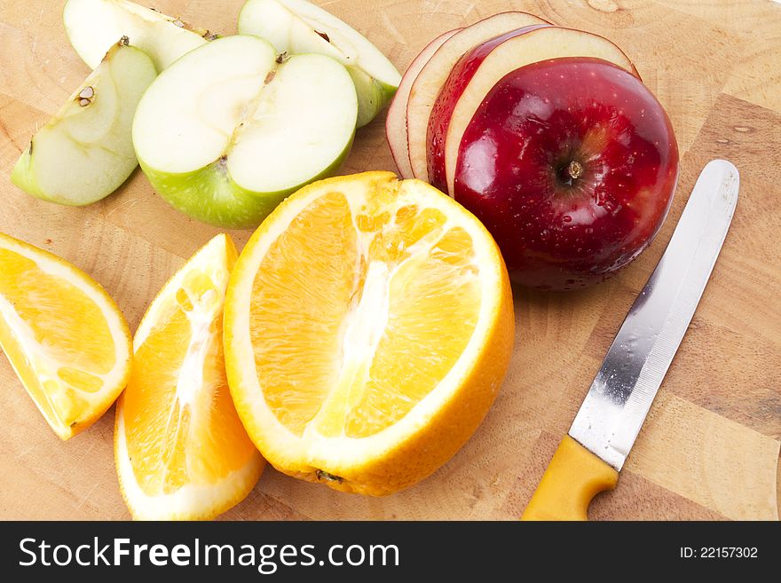 Mixed fruit on wood plate sliced and cut by yellow knife. Mixed fruit on wood plate sliced and cut by yellow knife.