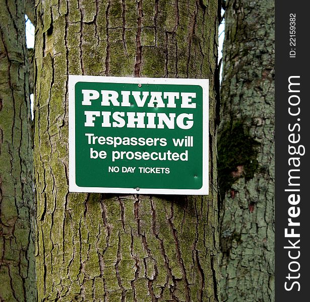 A sign displaying PRIVATE FISHING on a tree. A sign displaying PRIVATE FISHING on a tree