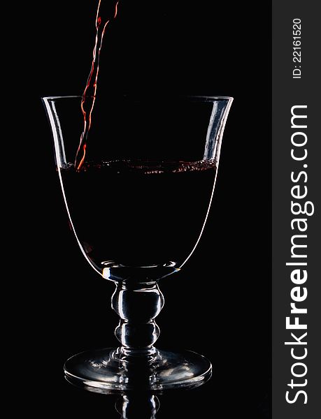 Red wine start to pour in a wineglass,low light photo