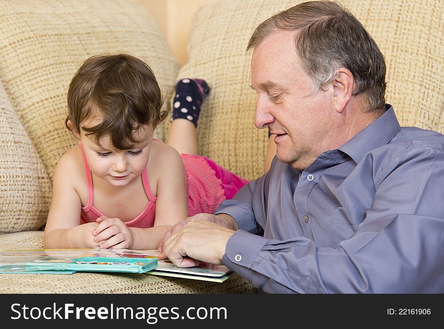 Grandfather reading with granddaughter