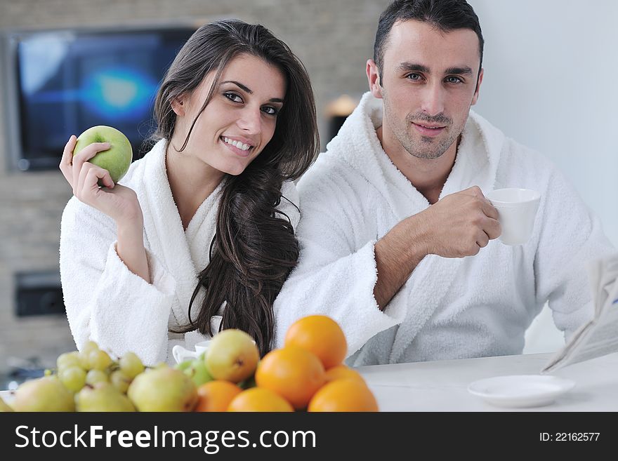 Young family couple read newspaper at kitchen in morning with fresh breakfast fruits food and coffee drink on table. Young family couple read newspaper at kitchen in morning with fresh breakfast fruits food and coffee drink on table