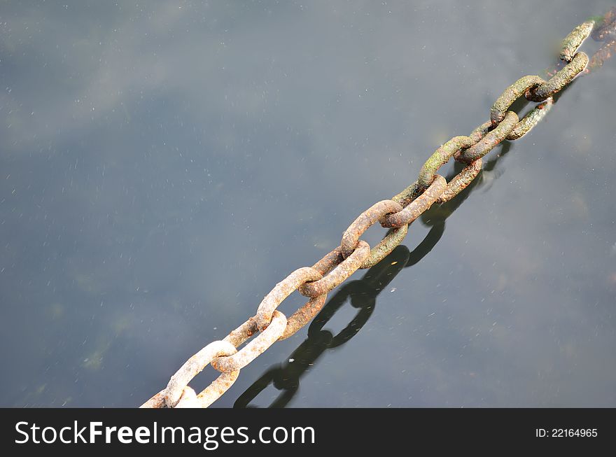 Rusty metal chain above and under water - with copy space. Rusty metal chain above and under water - with copy space