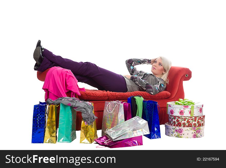 Tired woman lying on a red couch, around the shopping bags in packaging, isolated on white background. Tired woman lying on a red couch, around the shopping bags in packaging, isolated on white background