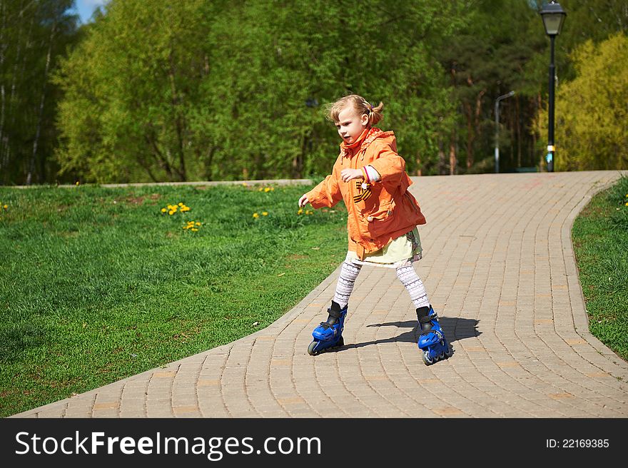 Girl rides on roller skates along the path of the park