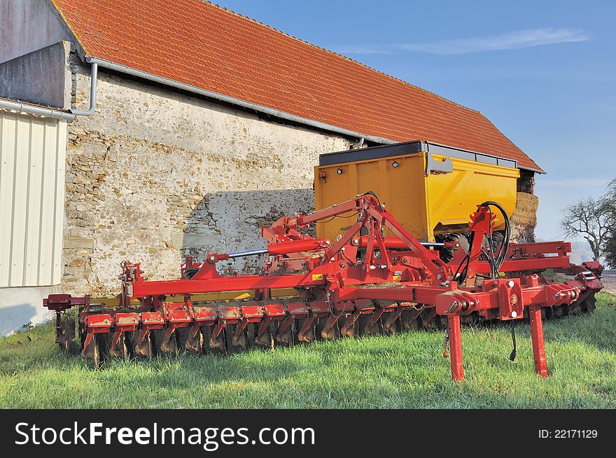 Harrow and trailer stored near a farm building. Harrow and trailer stored near a farm building