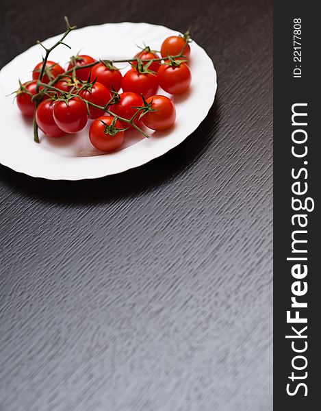 Cherrt tomatoes in a plate on a dark brown wooden table. Shallow depth of field. Cherrt tomatoes in a plate on a dark brown wooden table. Shallow depth of field.