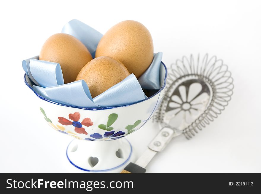 Eggs in bowl with kitchenware on white background