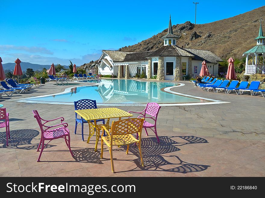 View of a small luxurious swimming pool with coloured table and chairs. View of a small luxurious swimming pool with coloured table and chairs