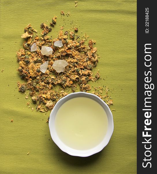 A bowl of flower tea ,white sugar with green background.