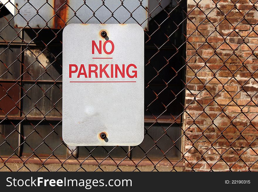 No parking sign on fence in front of old factory