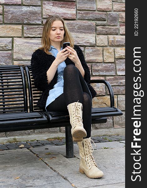 Young woman sitting at the park checking her messages. Young woman sitting at the park checking her messages