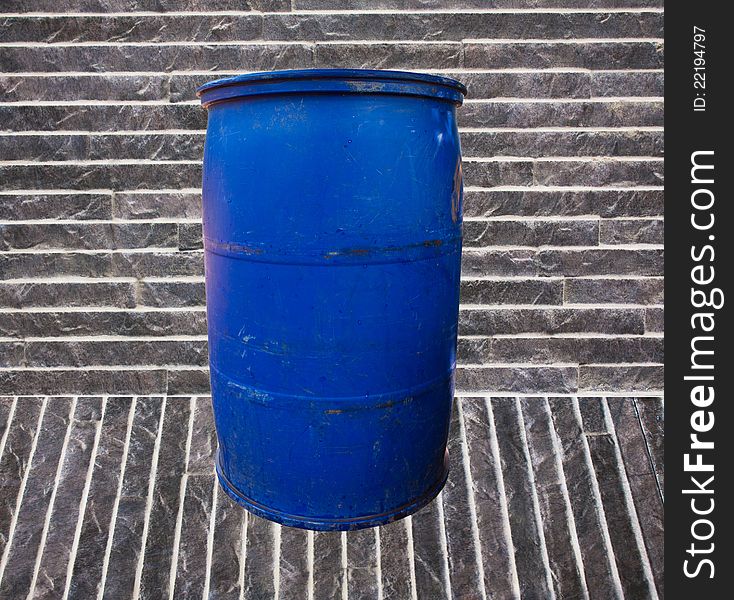 Blue garbage bucket on the stone floor and the stone background.