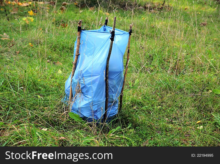 Plastic blue garbage bag on grass loaded with branches after cutting green hedge. Plastic blue garbage bag on grass loaded with branches after cutting green hedge.