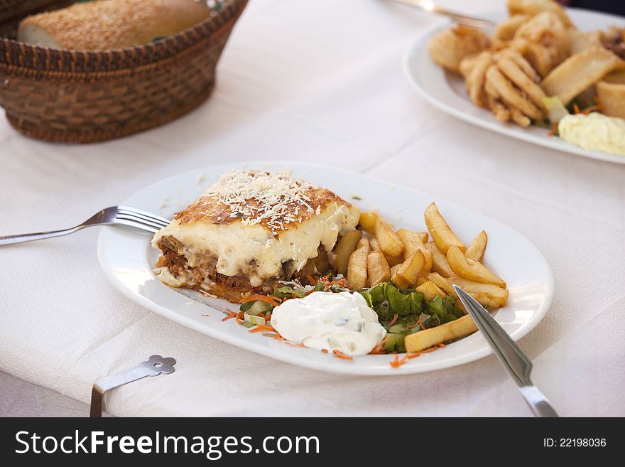 Portion of moussaka on a white plate. Portion of moussaka on a white plate