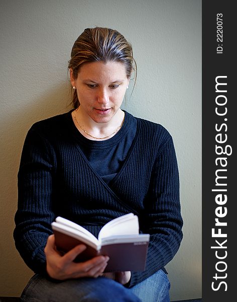 A young woman absorbed in her book with soft sideway lighting. A young woman absorbed in her book with soft sideway lighting