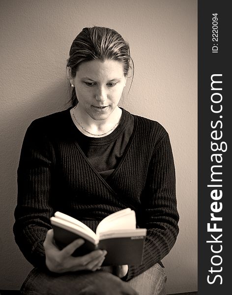 A young woman absorbed in her book with soft sideway lighting. A young woman absorbed in her book with soft sideway lighting