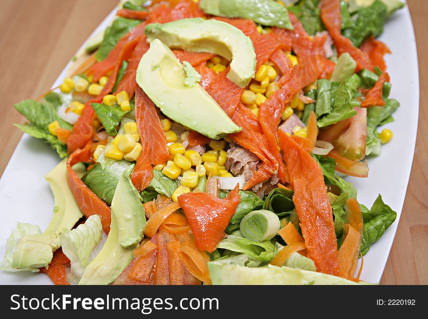 Salmon salad with sweet corn and vegetables on white dish