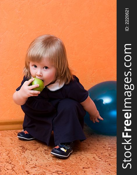 Cute little girl with green apple sitting on the floor. Cute little girl with green apple sitting on the floor