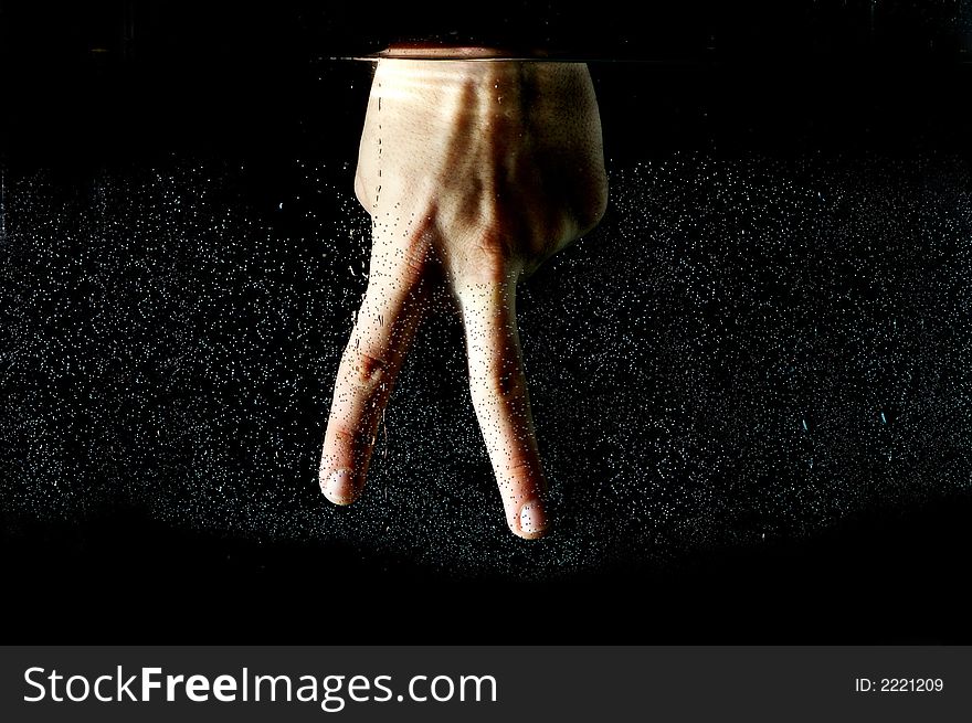 Photo of hand in the water on a black background.