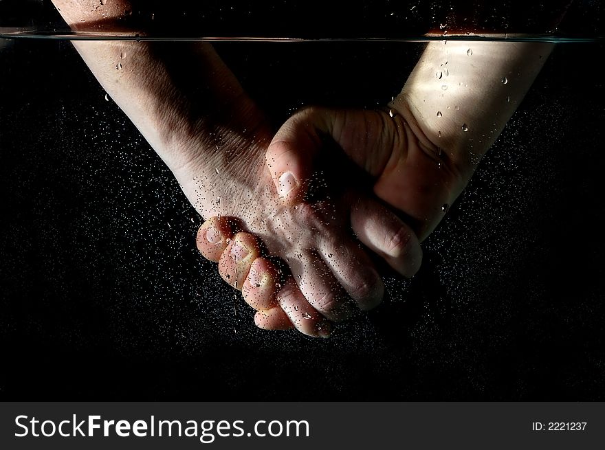 Photo of hands in the water on a black background.
