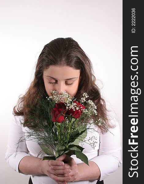 A young woman with dark hair smelling a bouquet of red roses. A young woman with dark hair smelling a bouquet of red roses