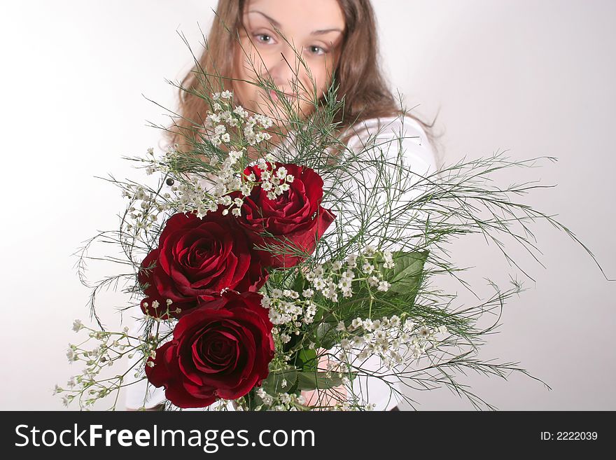 A young attractive brunette offering a bouquet of red roses. A young attractive brunette offering a bouquet of red roses