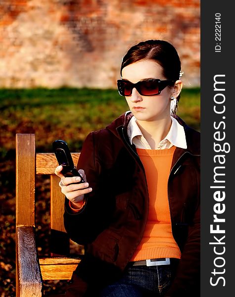 Photo of pretty female in sunshine light with cell phone. Photo of pretty female in sunshine light with cell phone.