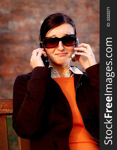 Photo of pretty female in sunshine light with two cell phones. Photo of pretty female in sunshine light with two cell phones.