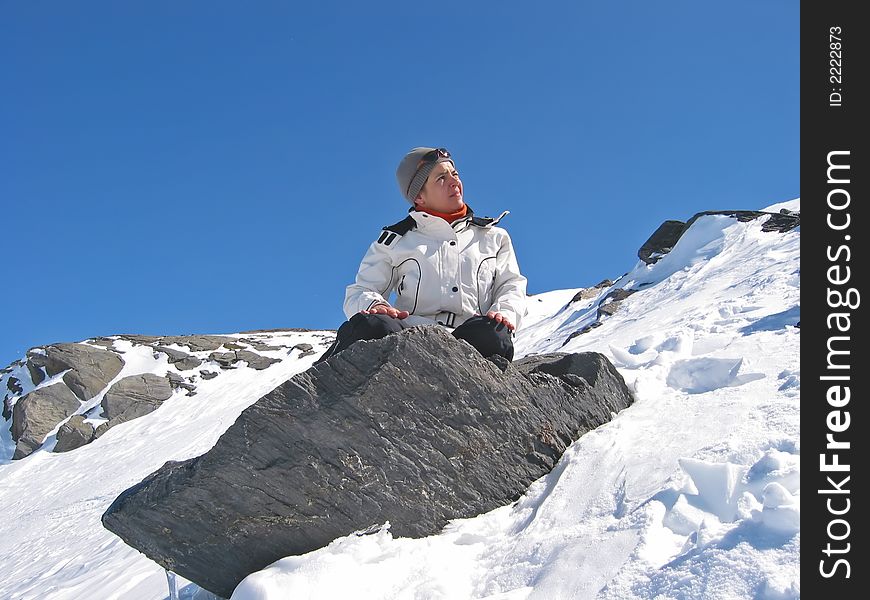 Woman in mountain with skiwears on a rock in the medium of snow. Woman in mountain with skiwears on a rock in the medium of snow